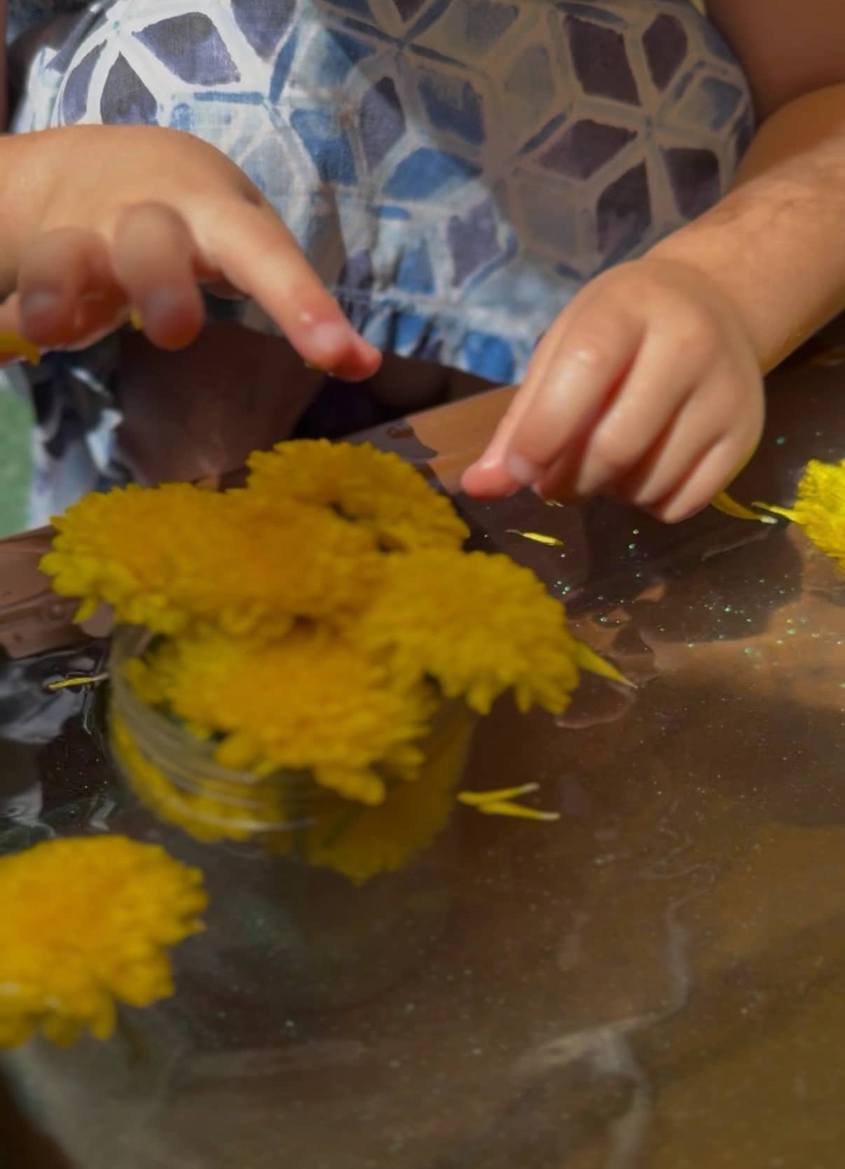Child exploring yellow flowers in water sensory play