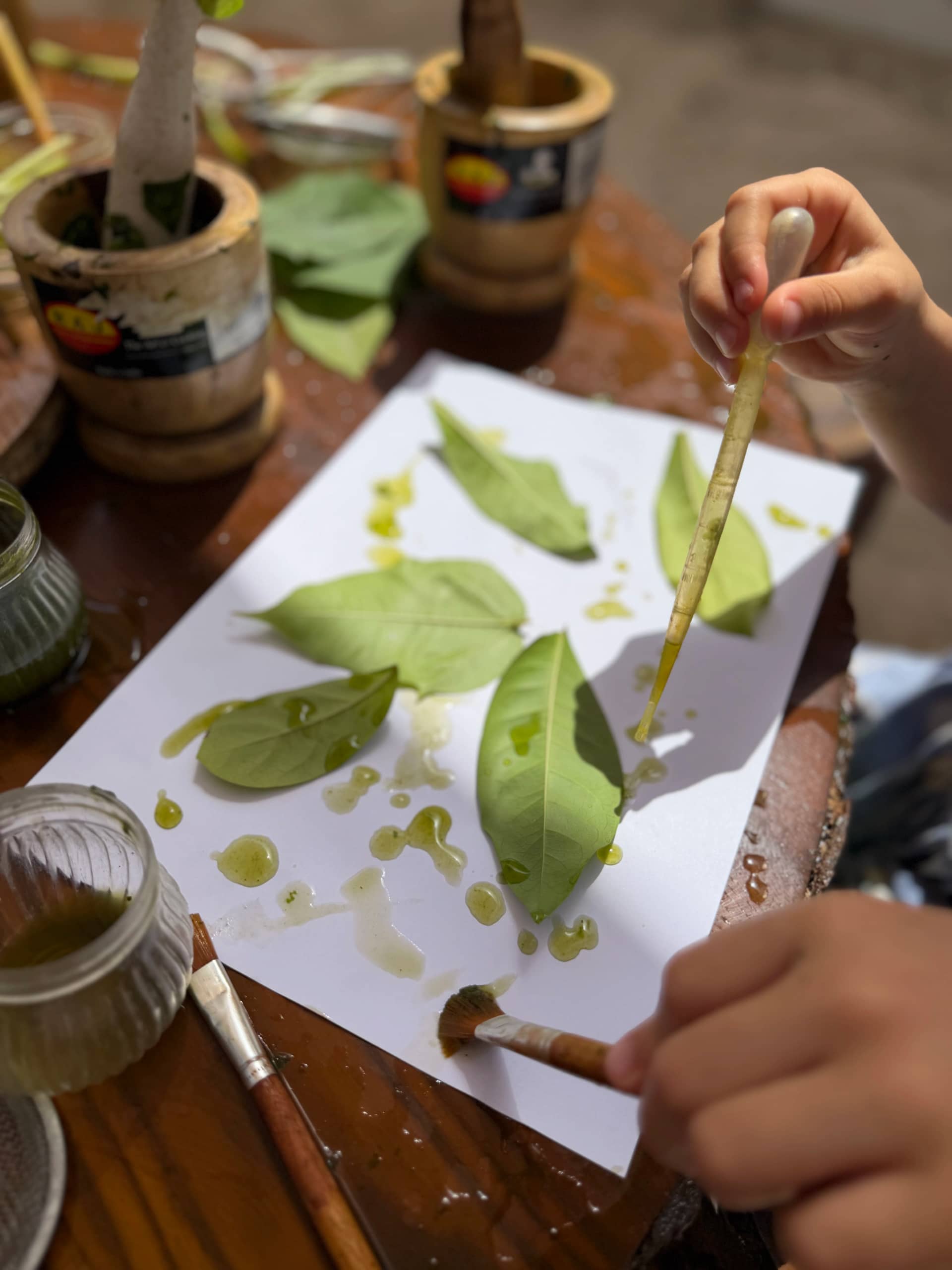 Child painting with leaves and natural pigments